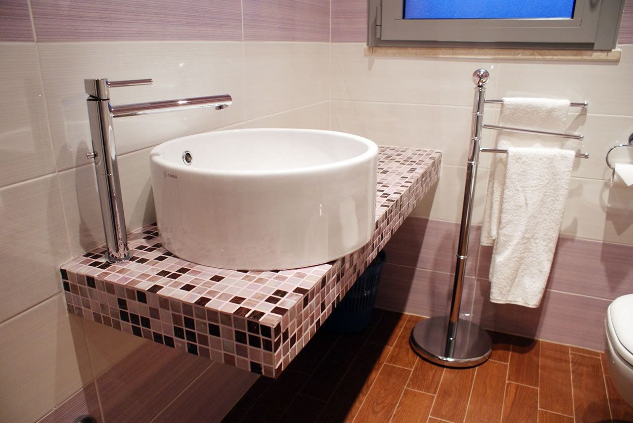 A bathroom with a white sink, chrome fixtures, and a tiled backsplash.