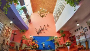 A dining area with wooden tables and chairs, a blue tiled wall, and hanging plants. - Casa Alfareros (Tlaquepaque)