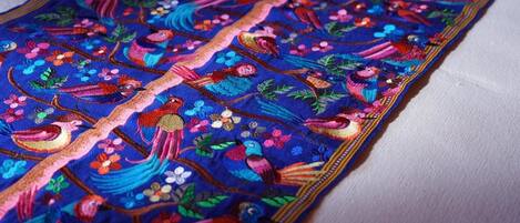 A detailed embroidered fabric with colorful birds and floral patterns.