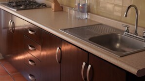 A modern kitchen with stainless steel appliances, a sink, and wooden cabinets. - Casa Alfareros (Tlaquepaque)
