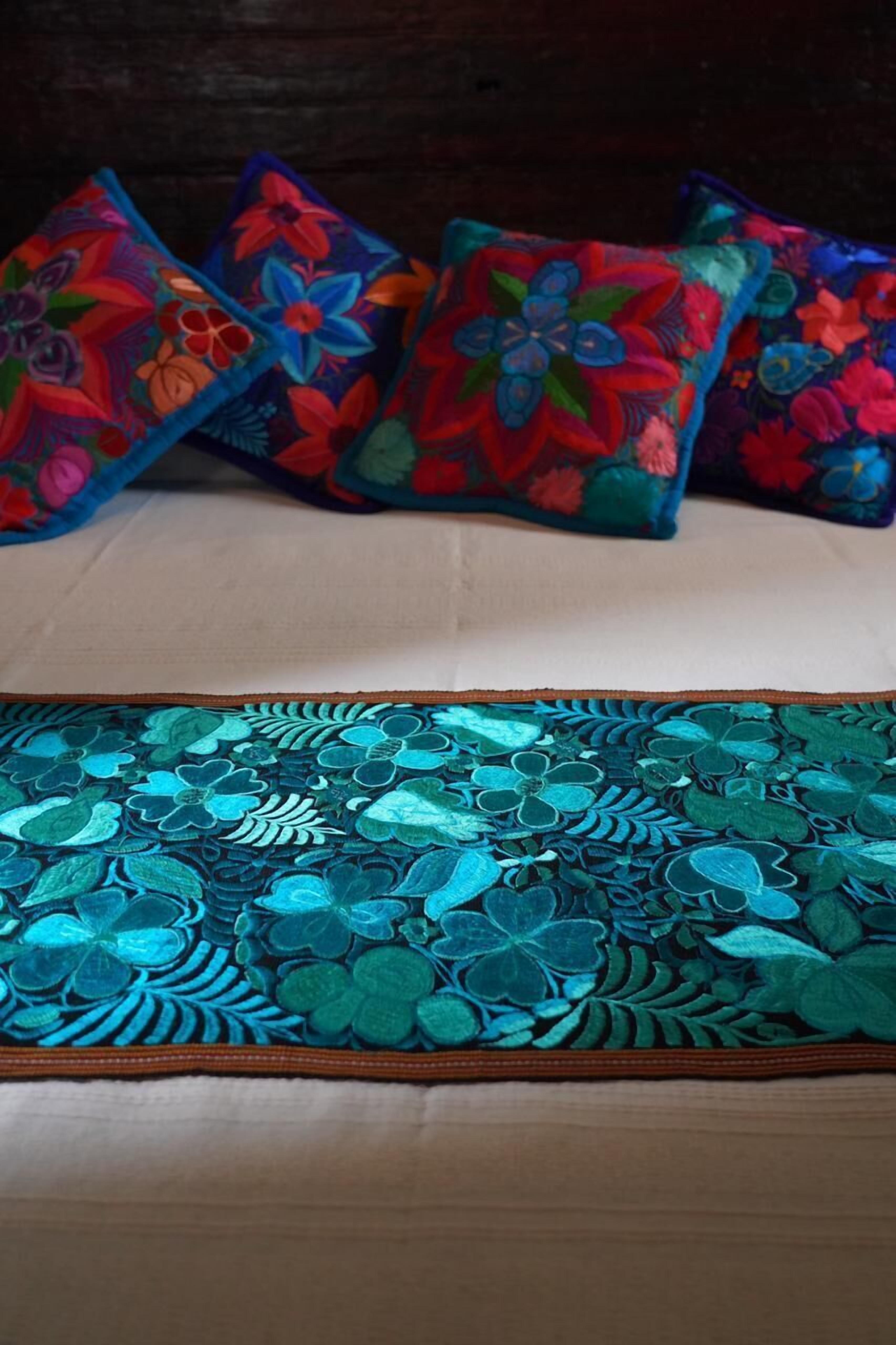 Un lit avec un drap blanc et deux oreillers à motifs floraux.