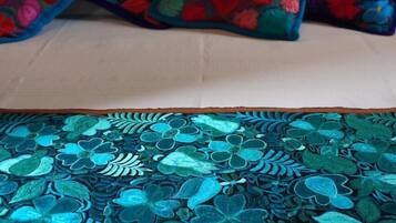 Un lit avec un drap blanc et deux oreillers à motifs floraux.