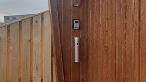 A wooden wall with a metal device and a small rectangular object mounted on it. - Black Beach Small Cottage (Sveitarfélagid Ölfus)