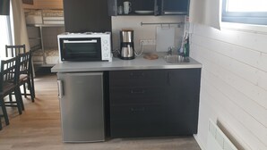 A compact kitchen with a built-in microwave, coffee maker, and a small refrigerator. - Black Beach Small Cottage (Sveitarfélagid Ölfus)