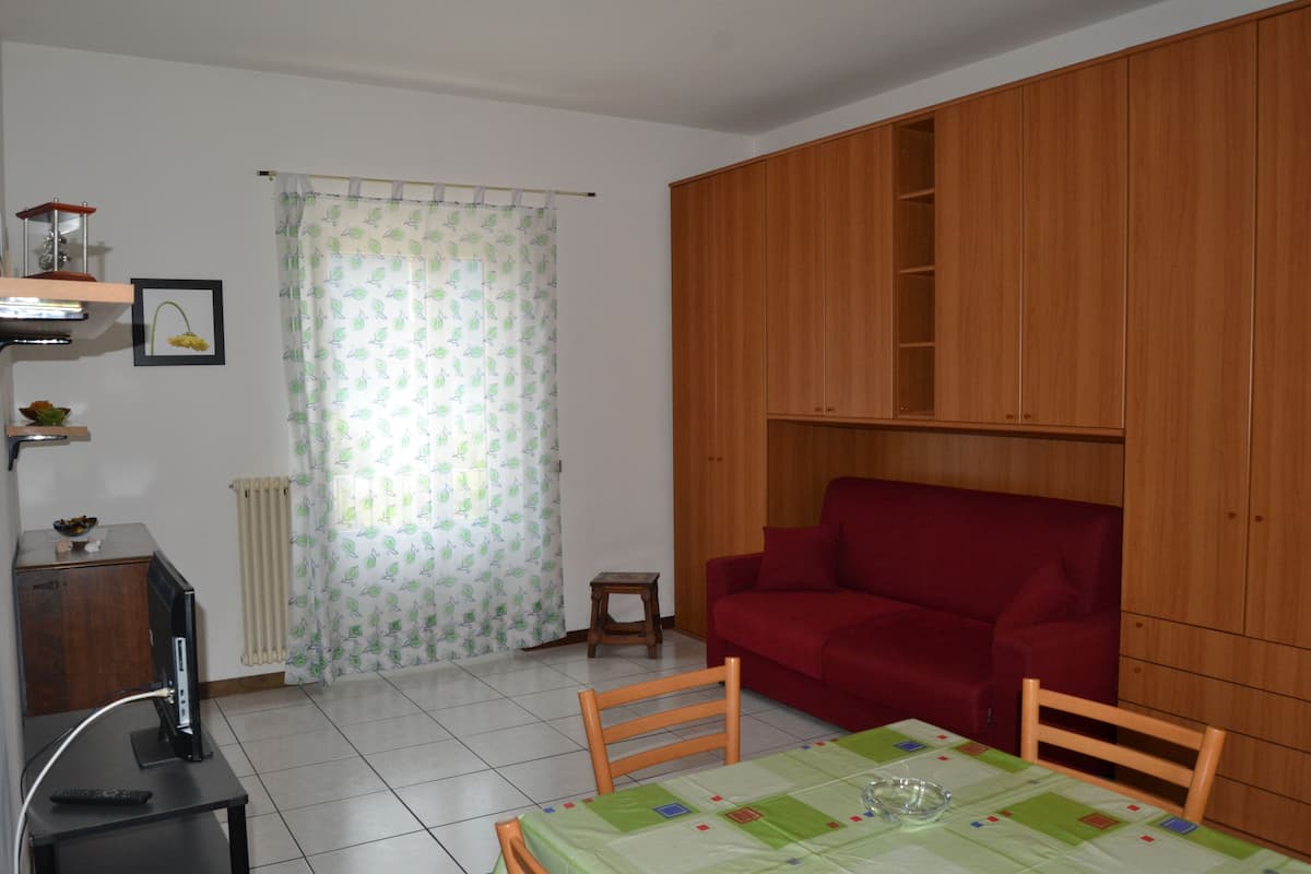 A compact living space with a dining table, a red sofa, and wooden cabinets.