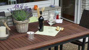 Une table en bois, une bougie, une bouteille de vin, un verre et un panier de lavande.