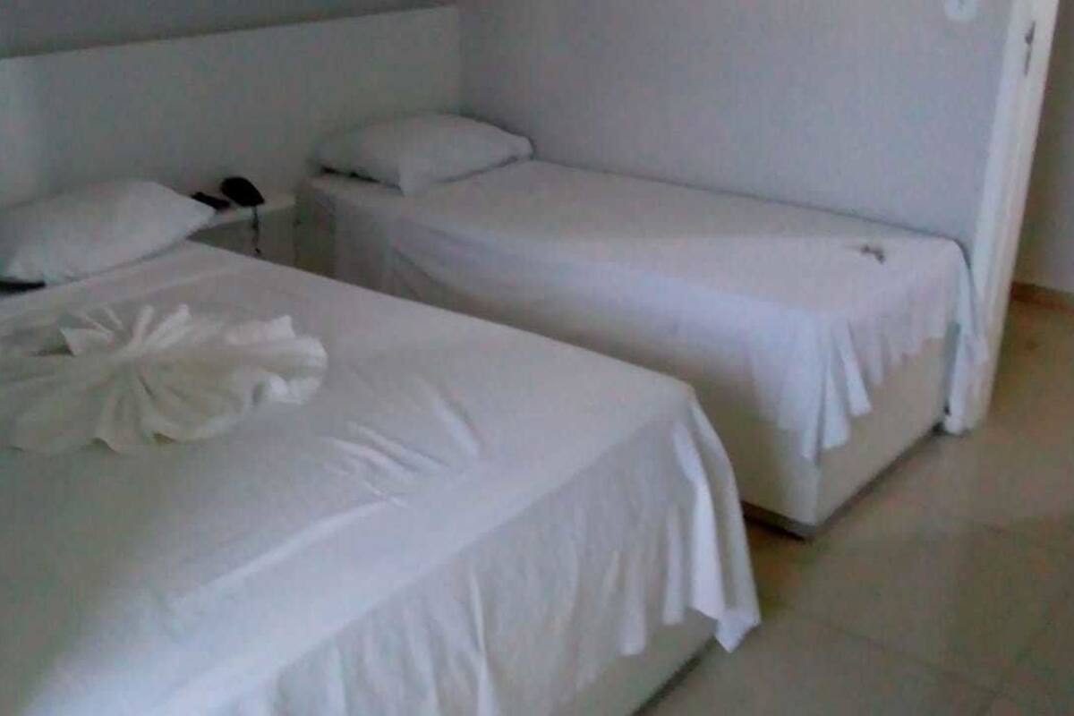 A hotel room with two single beds, each with white linens and pillows.