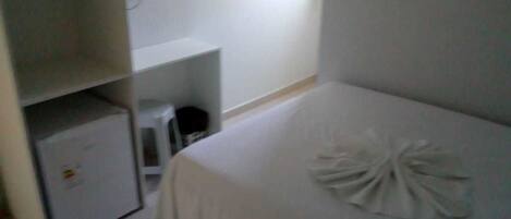 Una habitación de hotel con cama, un escritorio pequeño y un armario.
