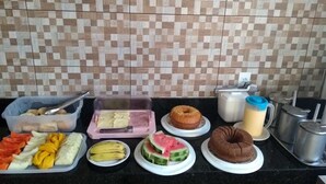 Ein Frühstücksbuffet mit verschiedenen Früchten, Gebäck und Getränken auf einer Küchenarbeitsplatte.