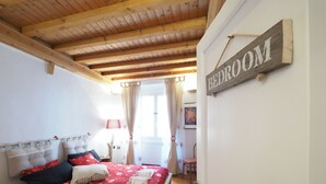 A bedroom with a wooden ceiling, a bed with a red floral bedspread, and a sign that reads "BEDROOM". - Caratteristica Dimora Della Galera (Genoa)