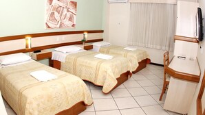 A hotel room with three beds, a desk, and a television. - Hotel Veneza (Brusque)