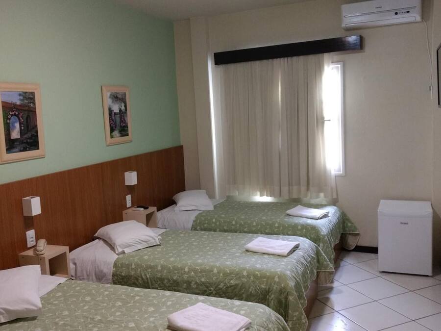 Habitación de hotel con dos camas, un escritorio pequeño, una silla, un televisor y una ventana con cortinas.