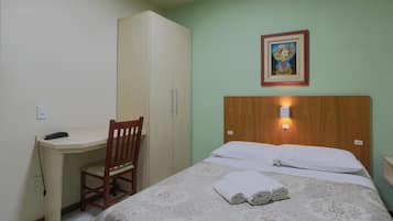 Een hotelkamer met een bed, een bureau, een stoel en een kledingkast.