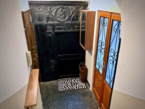 A black door with intricate carvings, a zebra-patterned mat, and a wooden bench. - Comoda Casa dell'Agnello zona Acquario (Genoa)