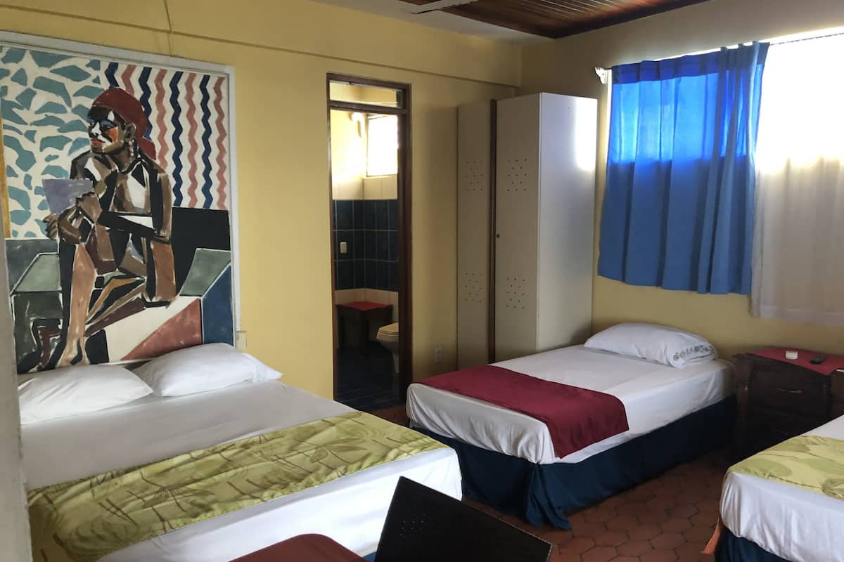 A hotel room with two beds, a bathroom, and a mural on the wall.