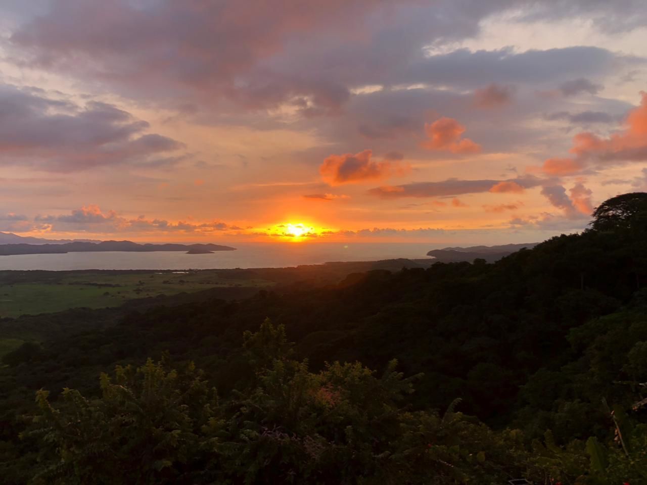 Un atardecer sobre un paisaje montañoso con una masa de agua al fondo.