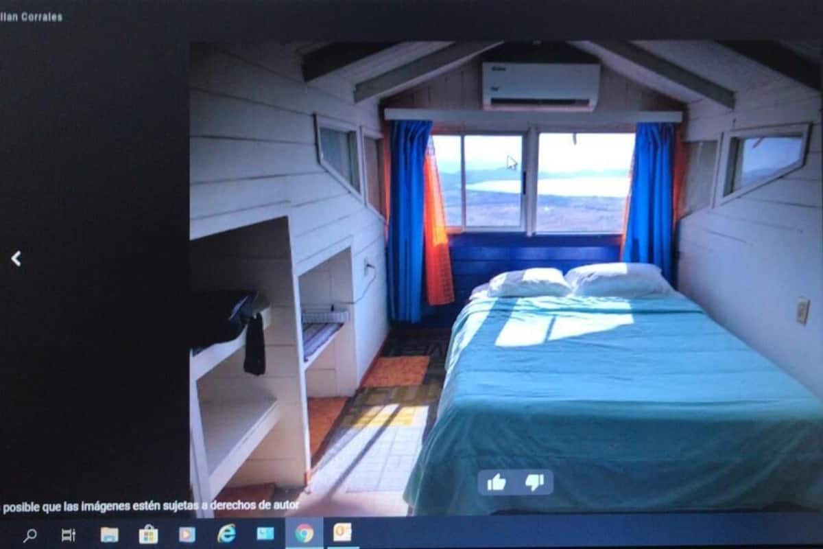 A small, compact room with a bed, a window, and a small table.