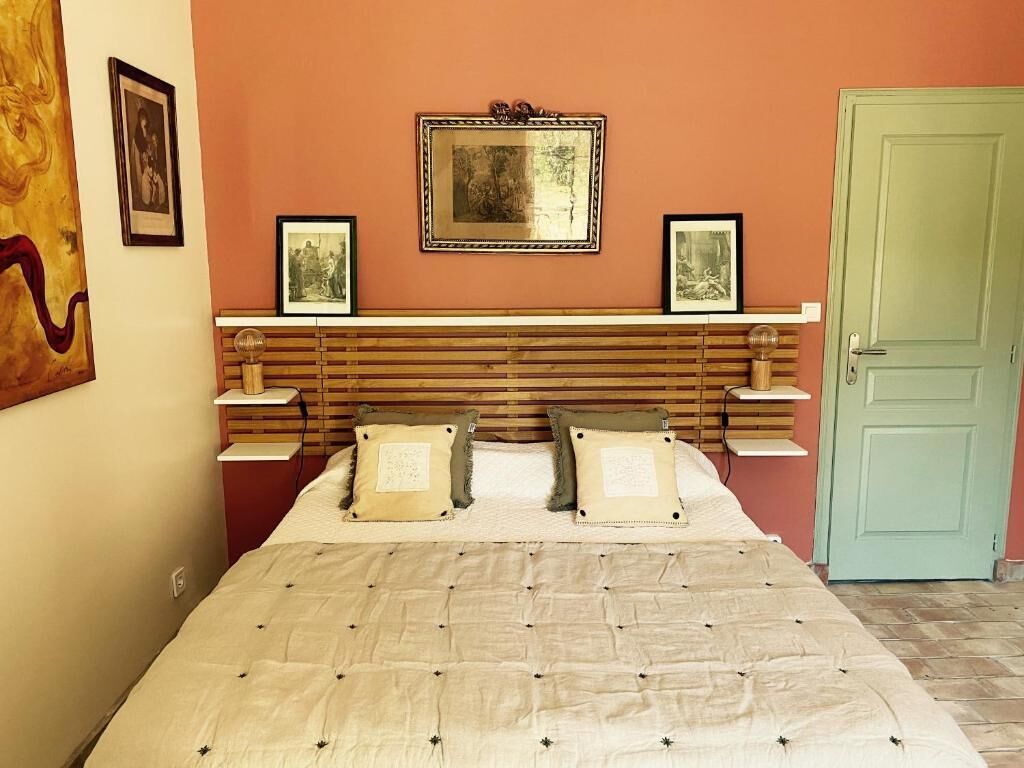 A bedroom with a wooden headboard, a bed with a beige quilt, two bedside tables, and a green door.