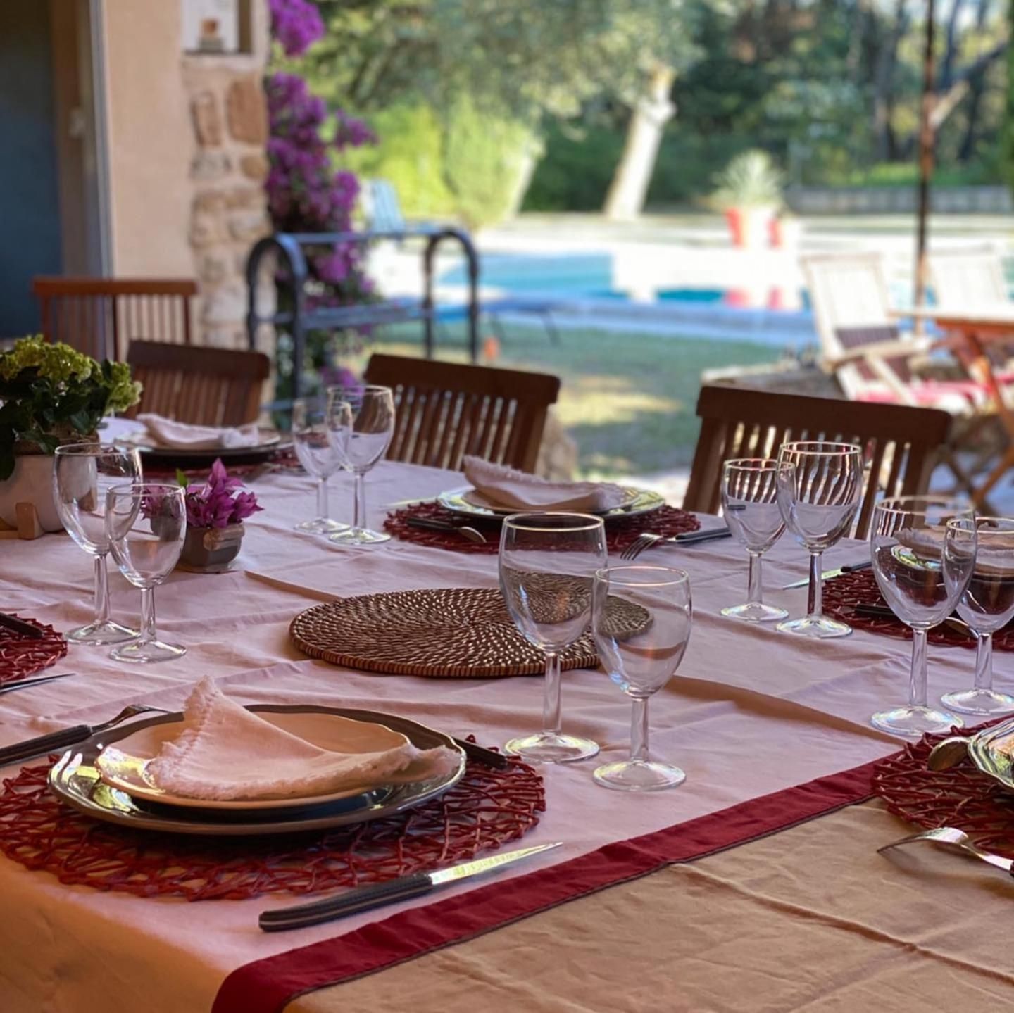 A table set for dining with multiple chairs, a view of the outdoors, and a pool in the background.