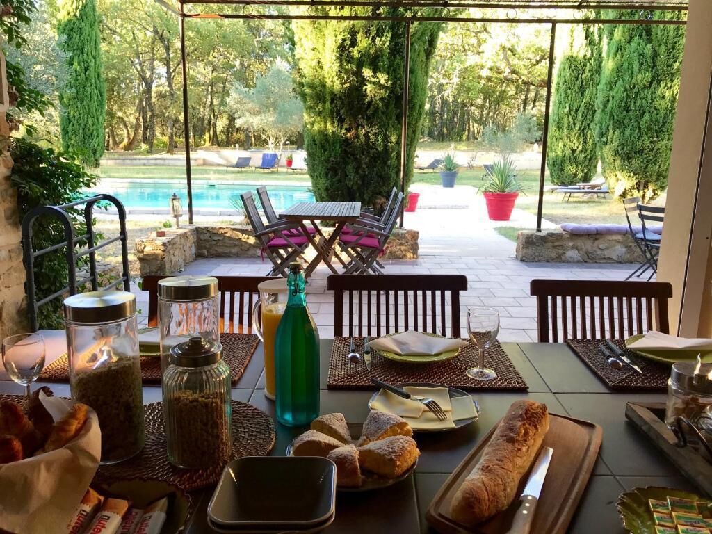 A dining table set for two with a view of a pool and garden.