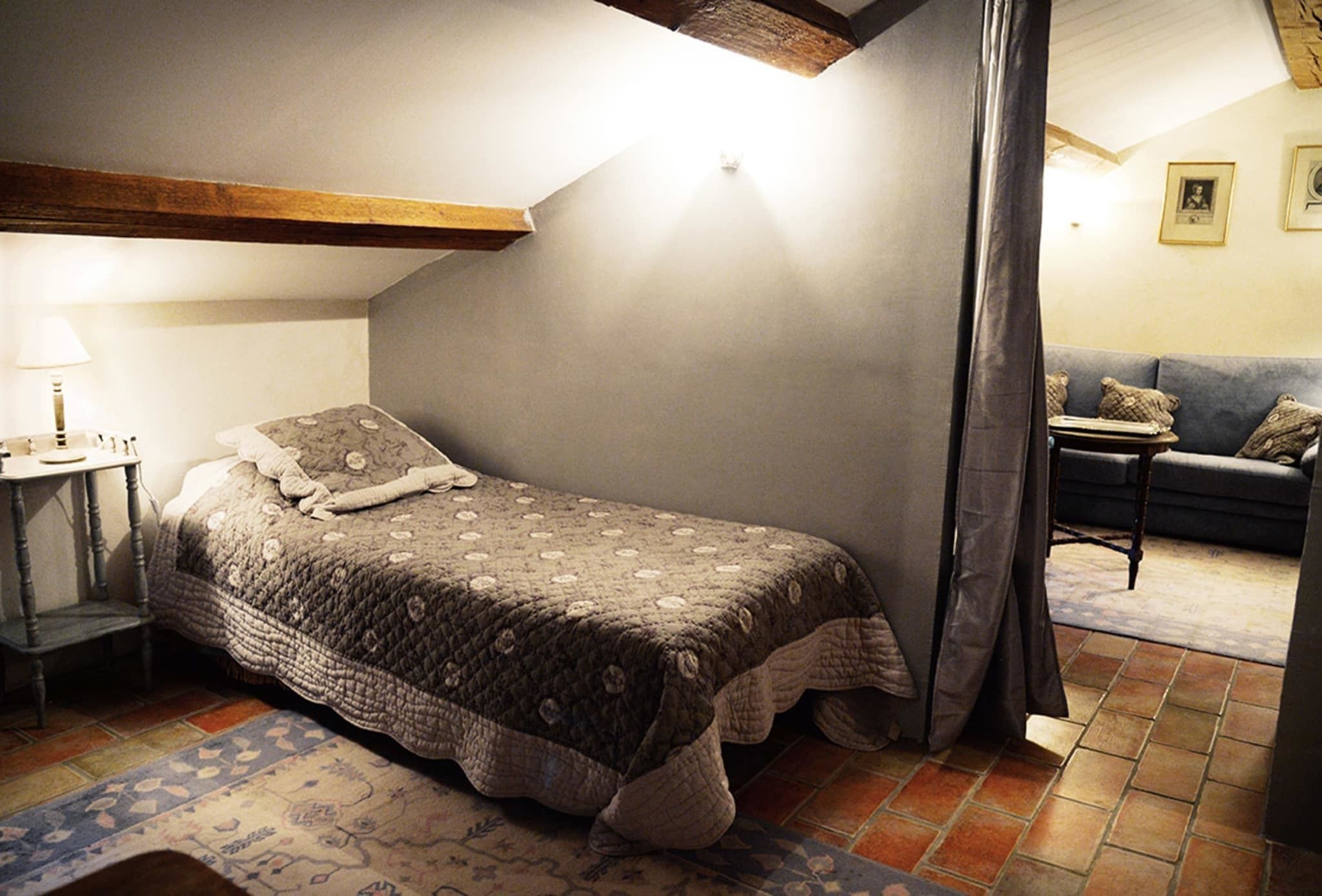 Ein Schlafzimmer mit Bett, Nachttisch, Lampe, einer Couch und einem kleinen Tisch.