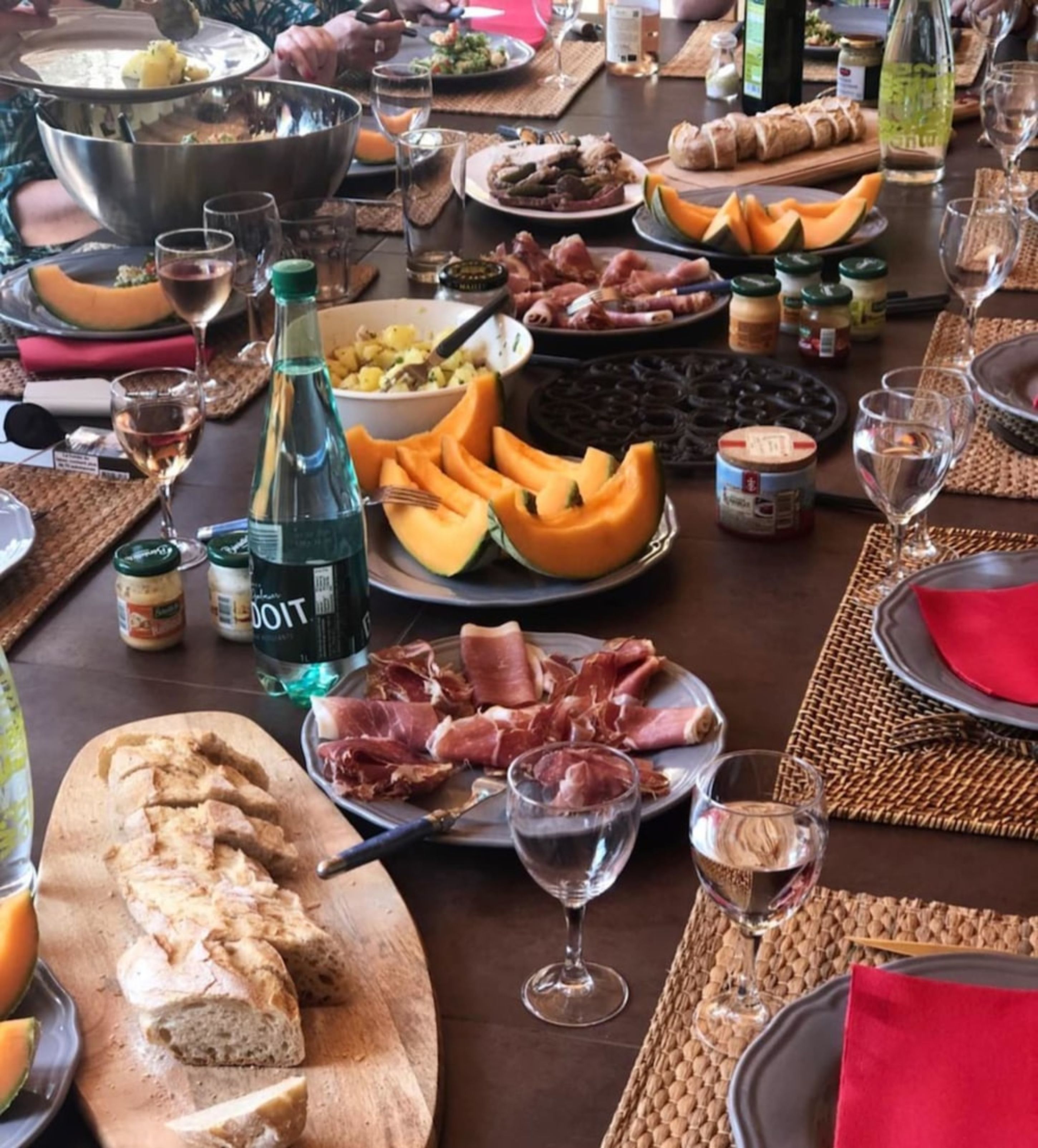 Ein gedeckter Tisch mit verschiedenen Speisen, darunter Aufschnitt, Gemüse und eine Wasserflasche.