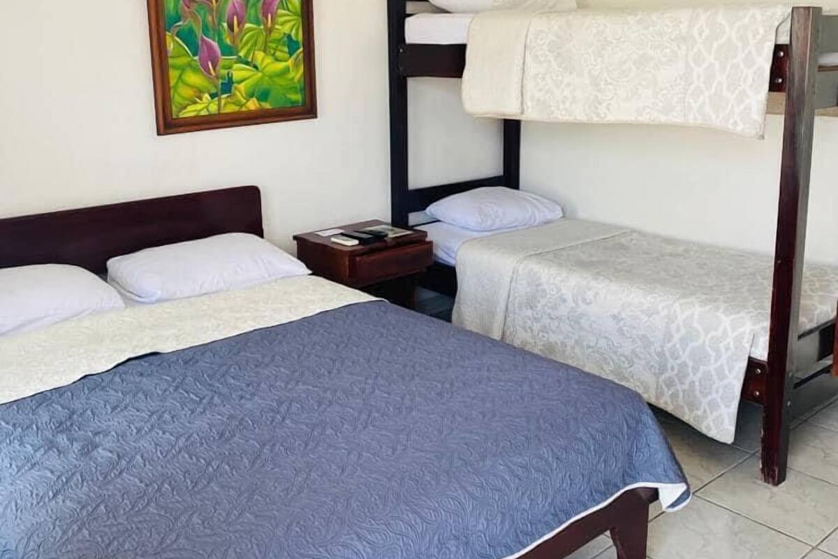 Une chambre avec un lit superposé, un lit simple et une table de chevet.