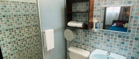 A bathroom with a toilet, sink, and shower area.