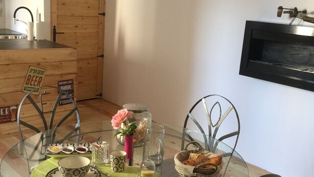 Un comedor con una mesa redonda de vidrio, sillas de metal y una puerta de madera al fondo.