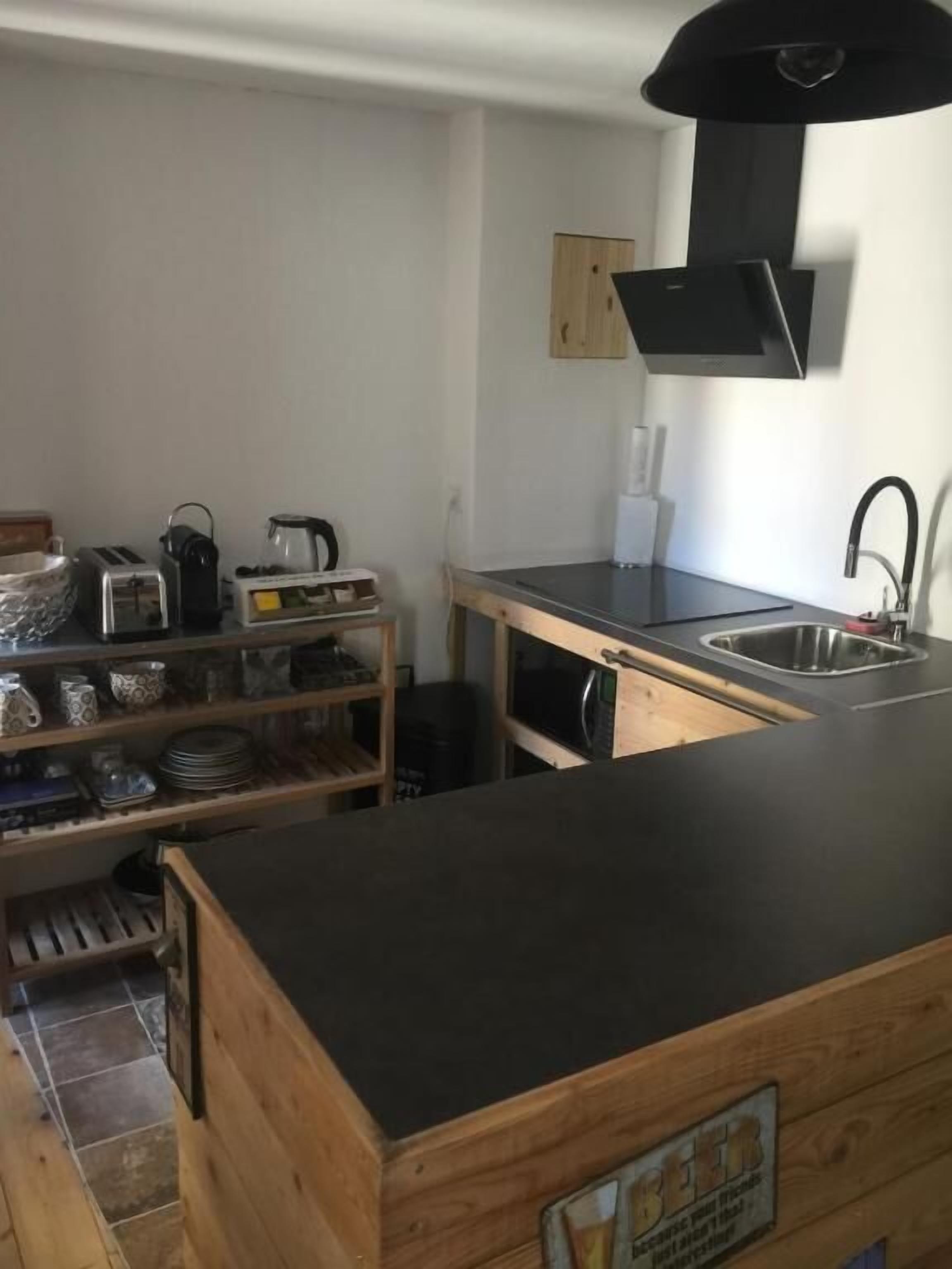 A compact kitchen with a black countertop, wooden cabinets, a built-in oven, and a sink.
