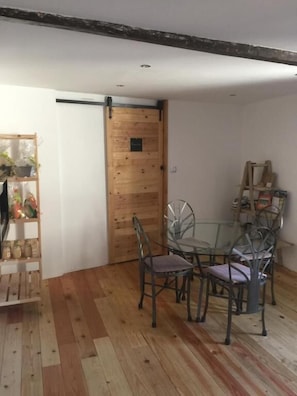 Un comedor con puerta de madera, mesa de vidrio y sillas de metal.
