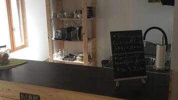 Ein Café-Interieur mit Holzwänden und einer schwarzen Theke, sowie verschiedenen Schildern, darunter 'FREE BEER TOMORROW' und 'BRING ME BEER'.
