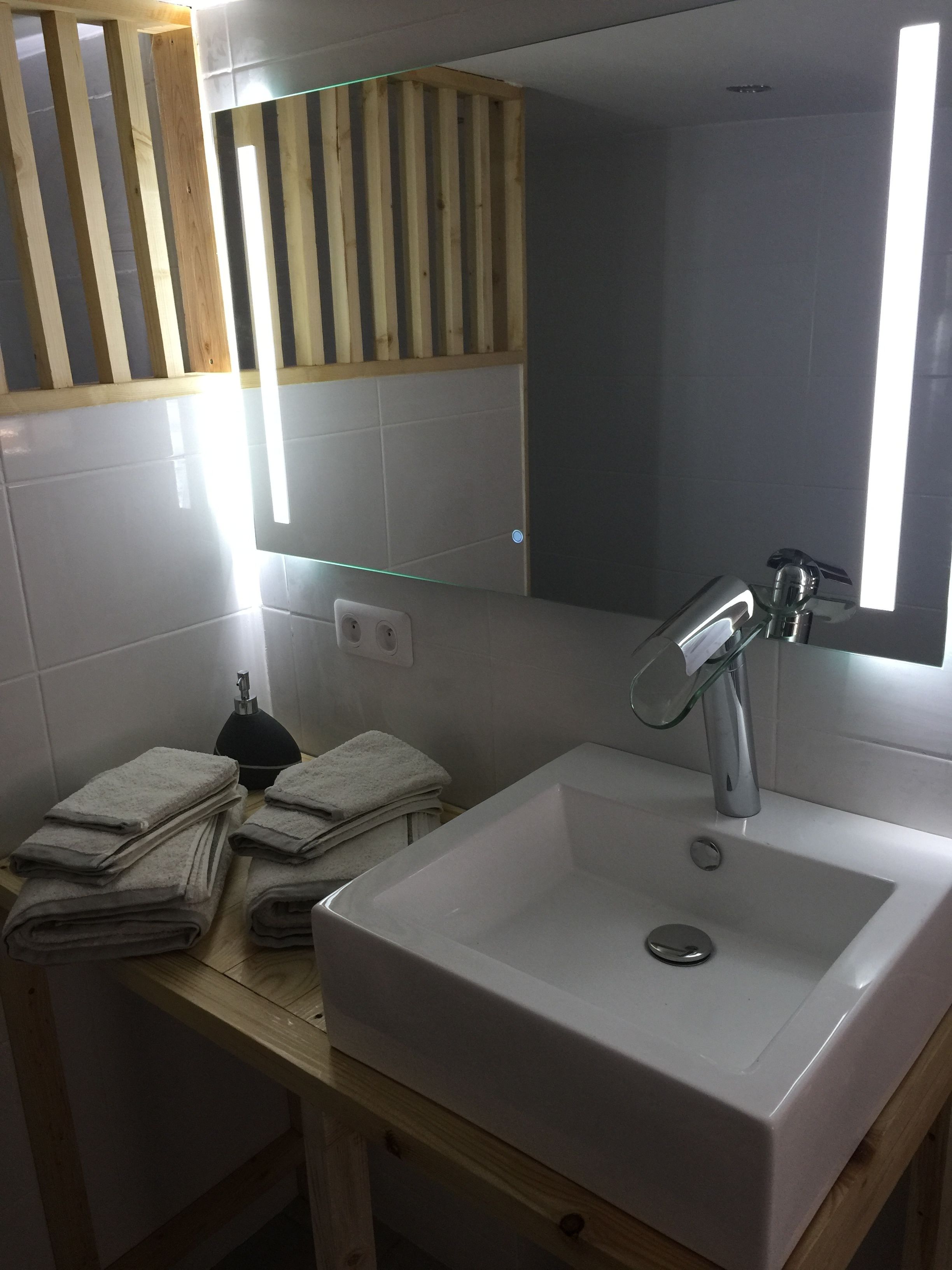 Un baño con un lavamanos blanco, un espejo y un toallero.