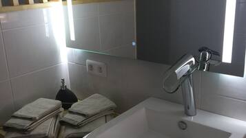 Un baño con un lavamanos blanco, un espejo y un toallero.