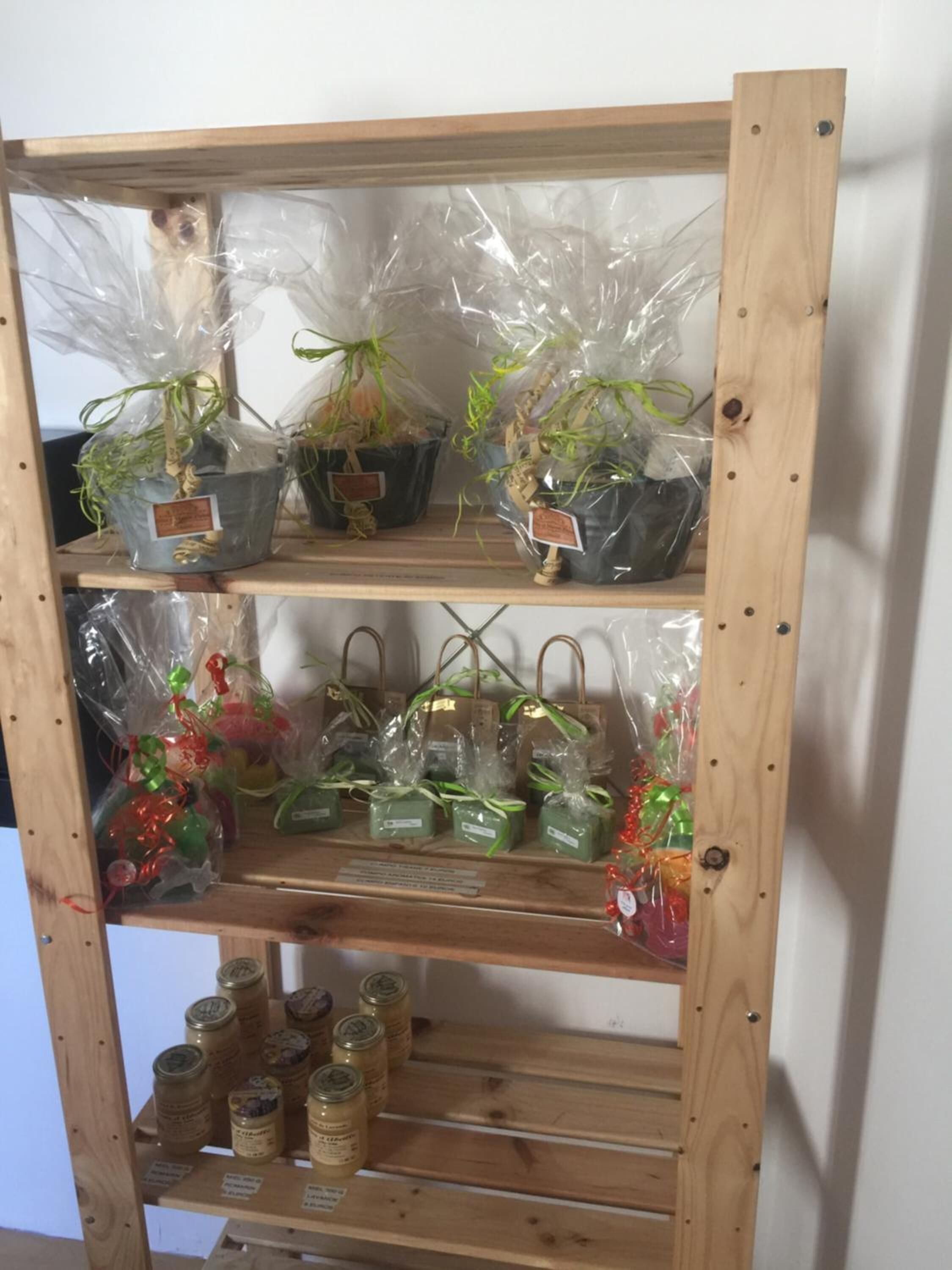 Uno scaffale di legno con piante in vaso, piccoli sacchetti regalo e barattoli.