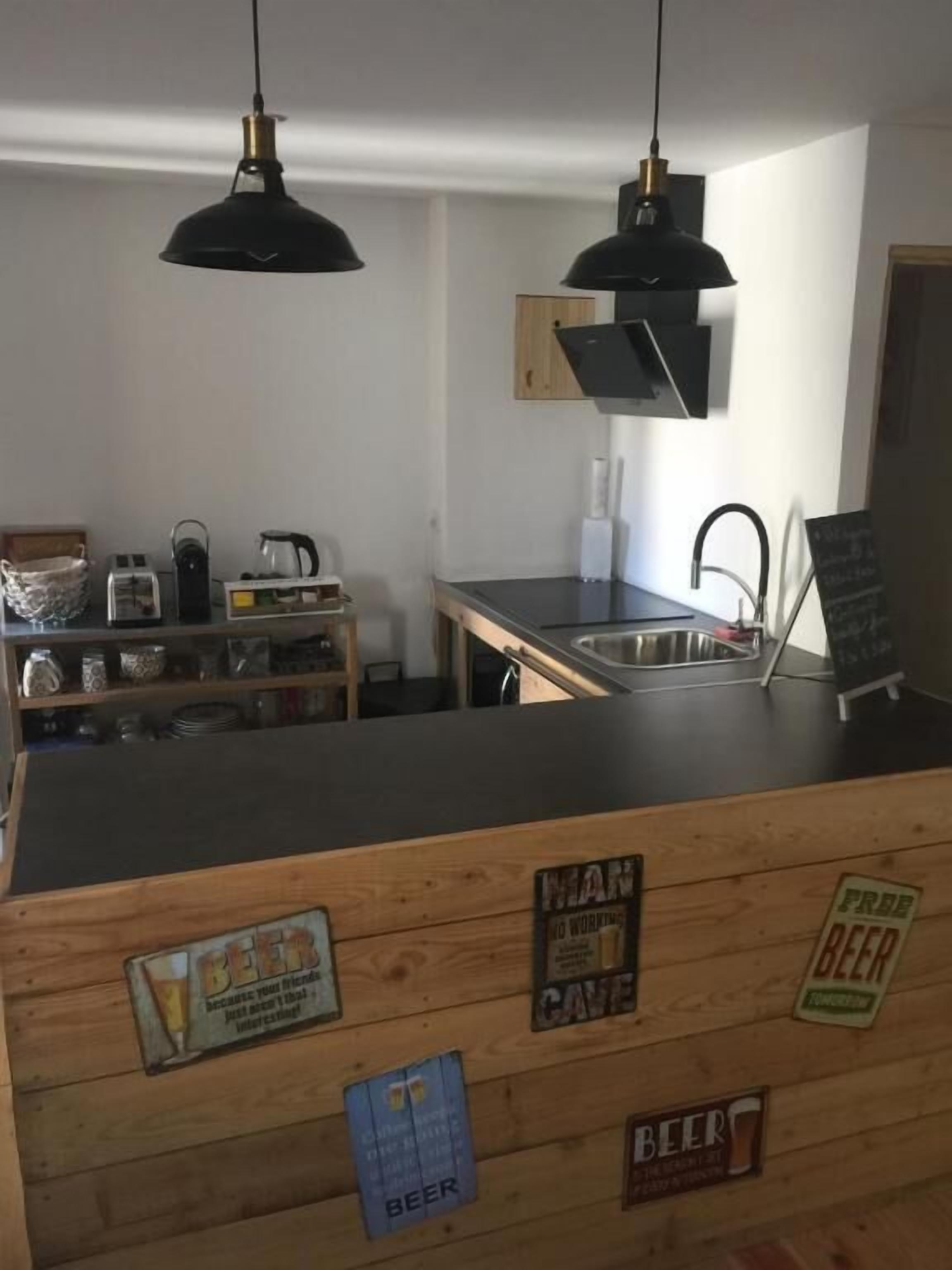 A kitchen with wooden cabinets, a black countertop, and hanging pendant lights. There are signs on the cabinets indicating 'FREE BEER' and 'MAN CAVE'.