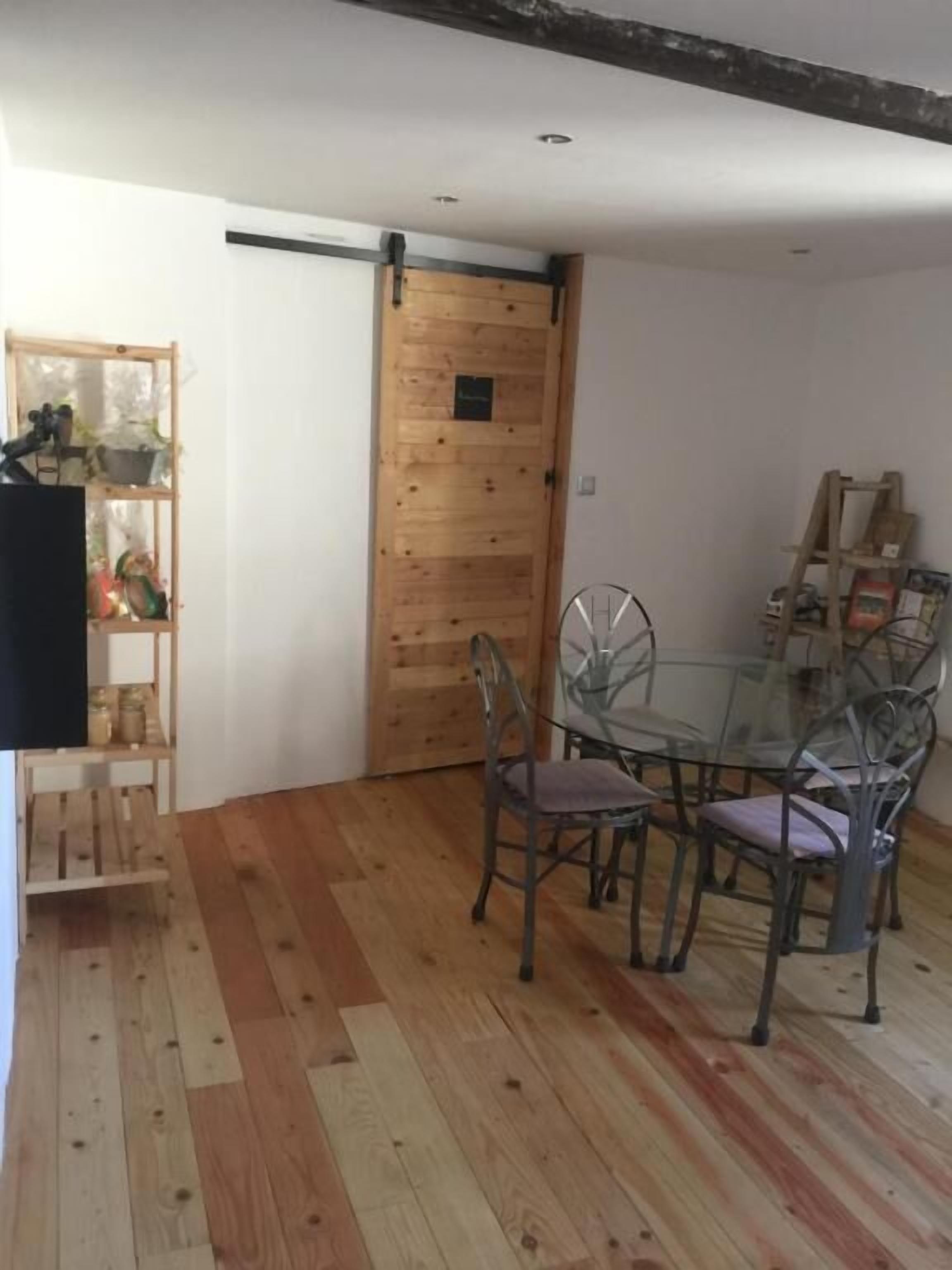 Un coin repas avec une porte en bois, une table en verre et des chaises en métal.