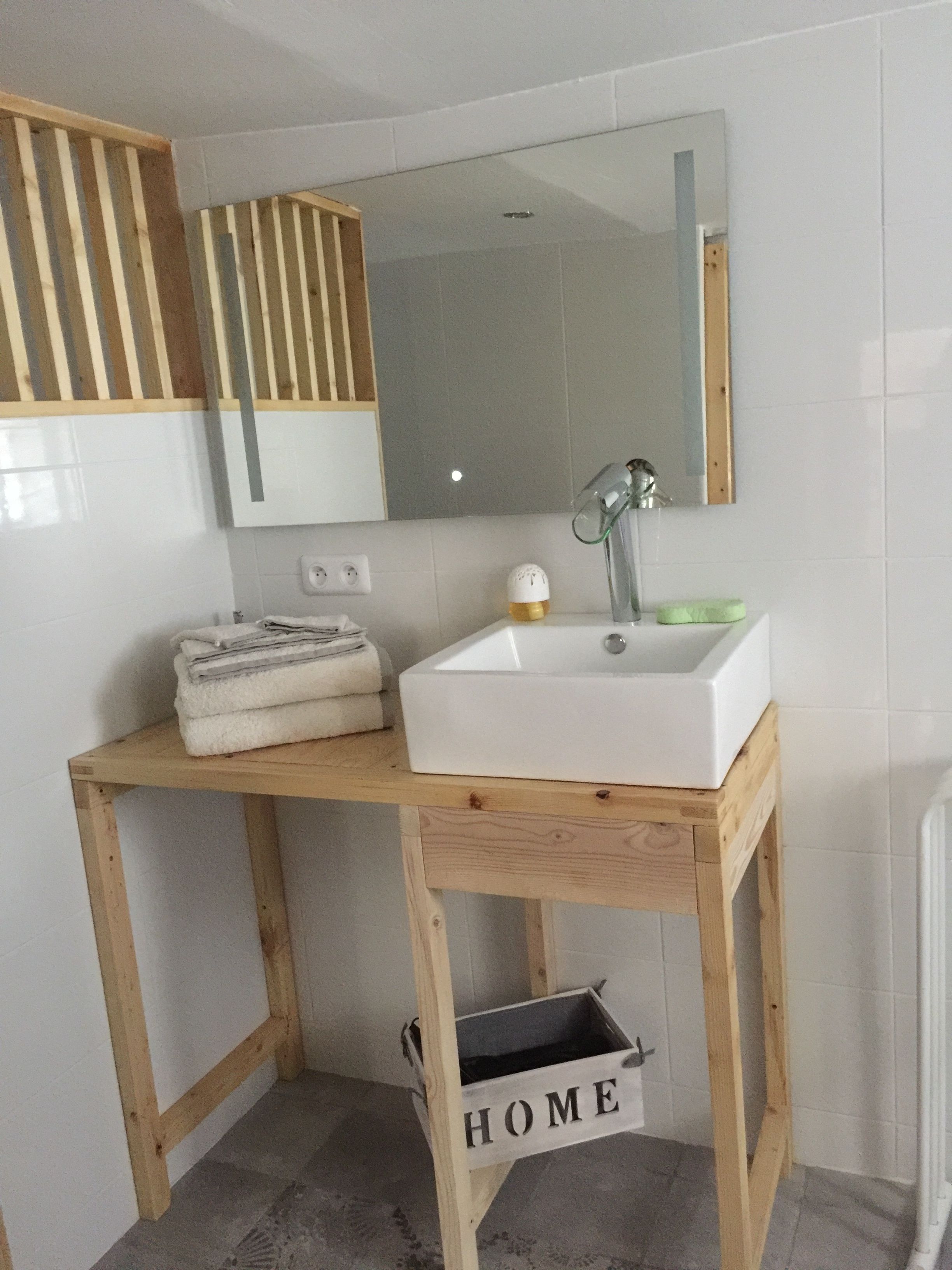Une salle de bain avec un meuble-lavabo en bois, un lavabo blanc, un miroir et une pile d’serviettes.