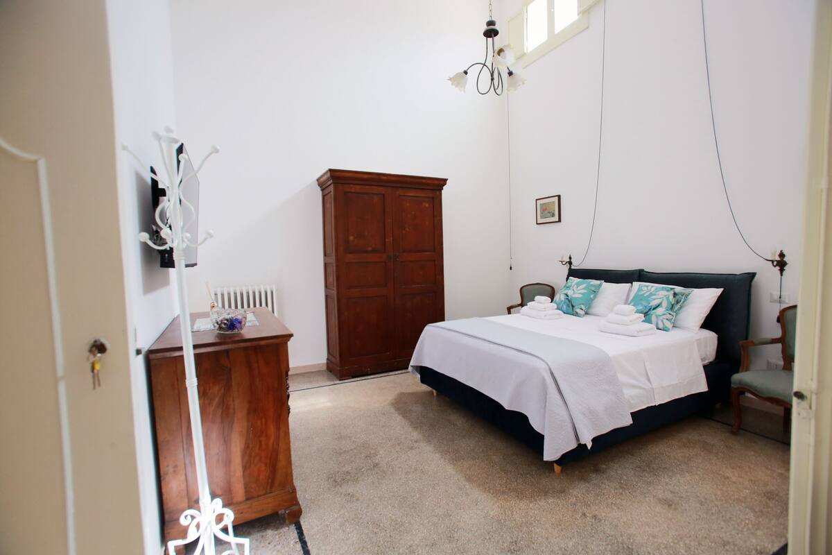 Quarto com cama, guarda-roupa de madeira, cadeira e candelabro.