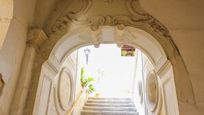 An ornate doorway with a staircase leading to a bright area outside. - Palazzo Sambiasi (Lecce)