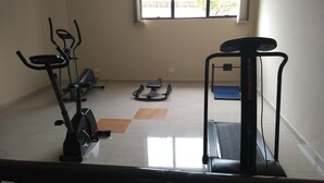 Un gimnasio con cintas de correr, bicicletas estáticas y una máquina de remo.