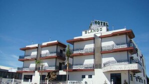 Un hotel de varios pisos con balcones y un cartel que dice 'HOTEL BLANCO'.