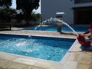 A swimming pool with a water feature and a decorative fish statue. - Blanco Palace Hotel (São José dos Campos)