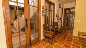 Un pasillo con puerta de madera, una escalera y un comedor con mesa y sillas.