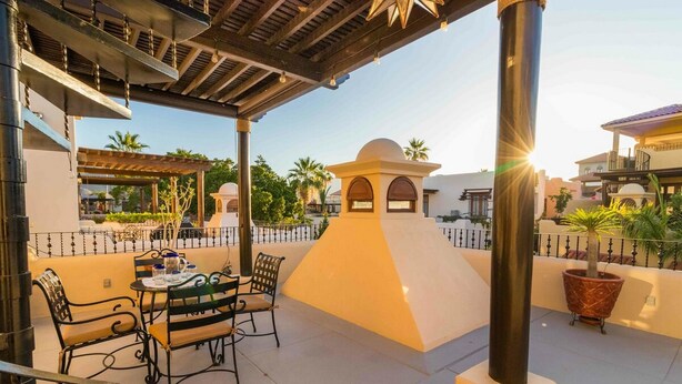 Un patio al aire libre con mesa y sillas, una pérgola y un muro decorativo.
