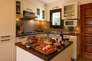 A kitchen with a central island, wooden cabinets, a microwave, and a window.