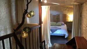 Una habitación rústica con techo de madera, una cama con almohadas, una silla y una mesa.