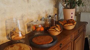 A wooden buffet table with various baked goods, including pies and pastries, and a potted plant with dried branches.