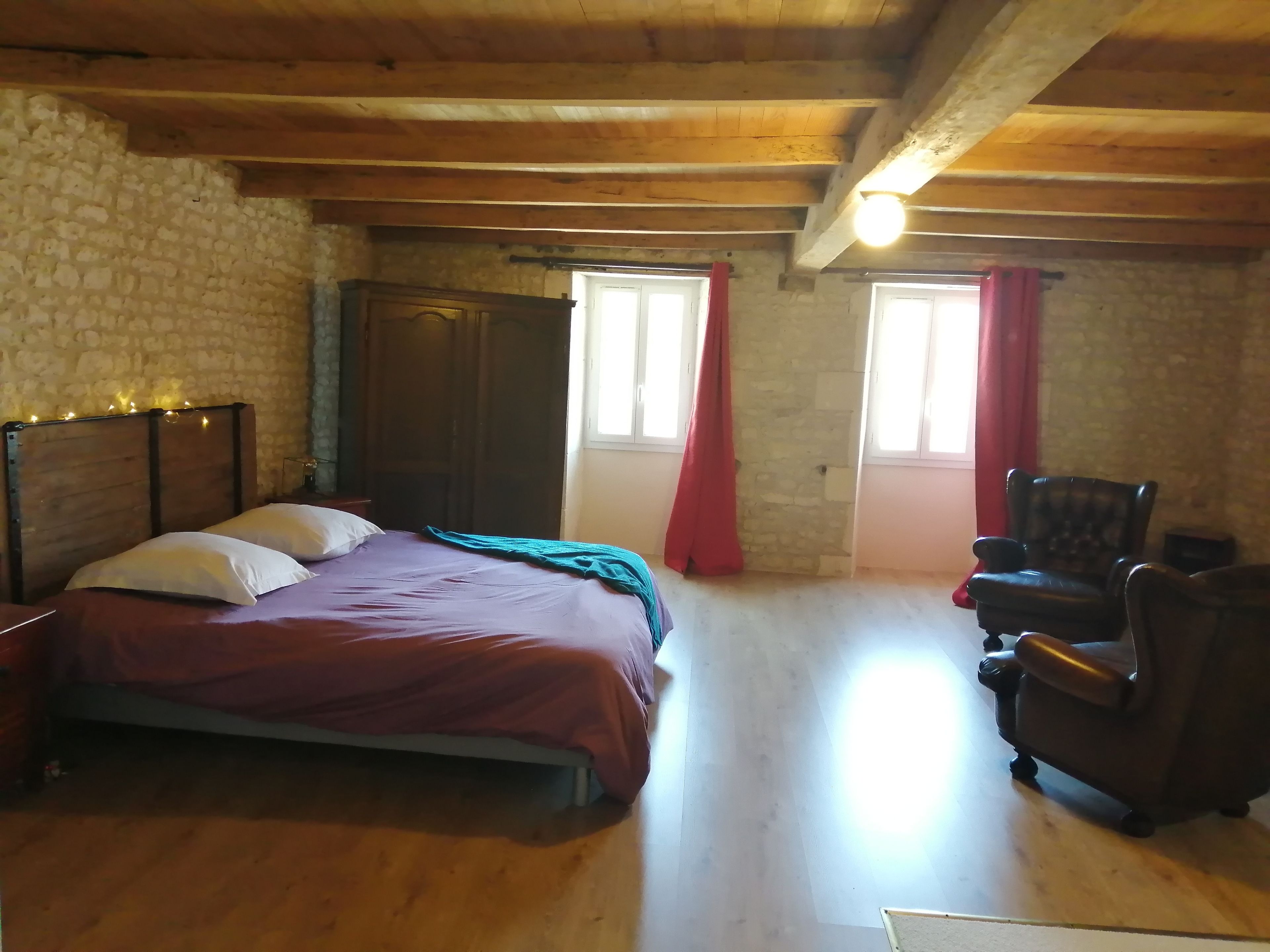 Ein Zimmer mit einem Bett, einem Sessel, einem Kleiderschrank und einer Tür.