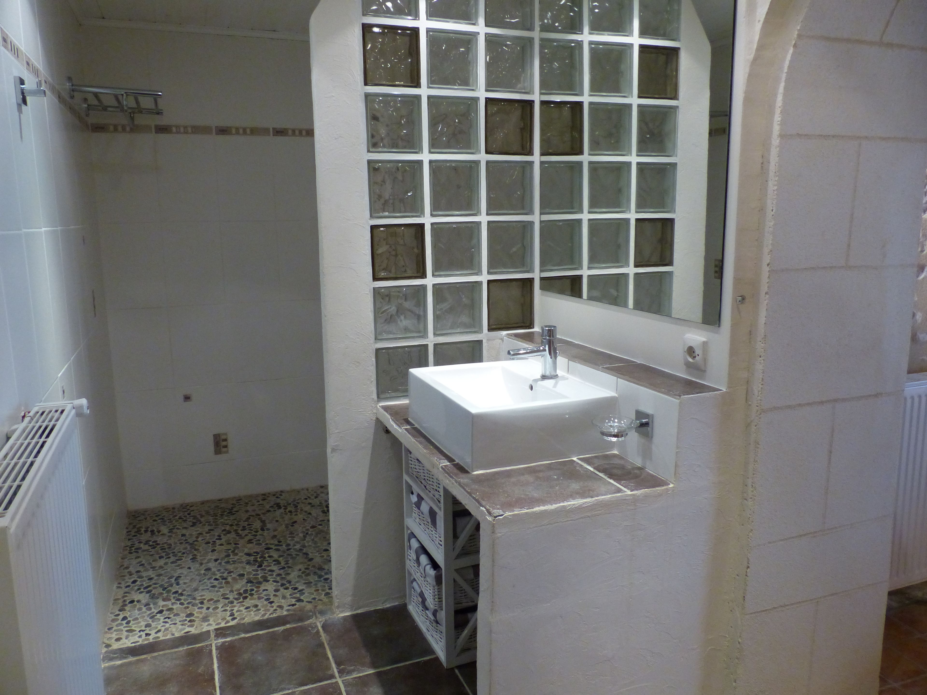 A bathroom with a white sink, a mirror, and a shower area.